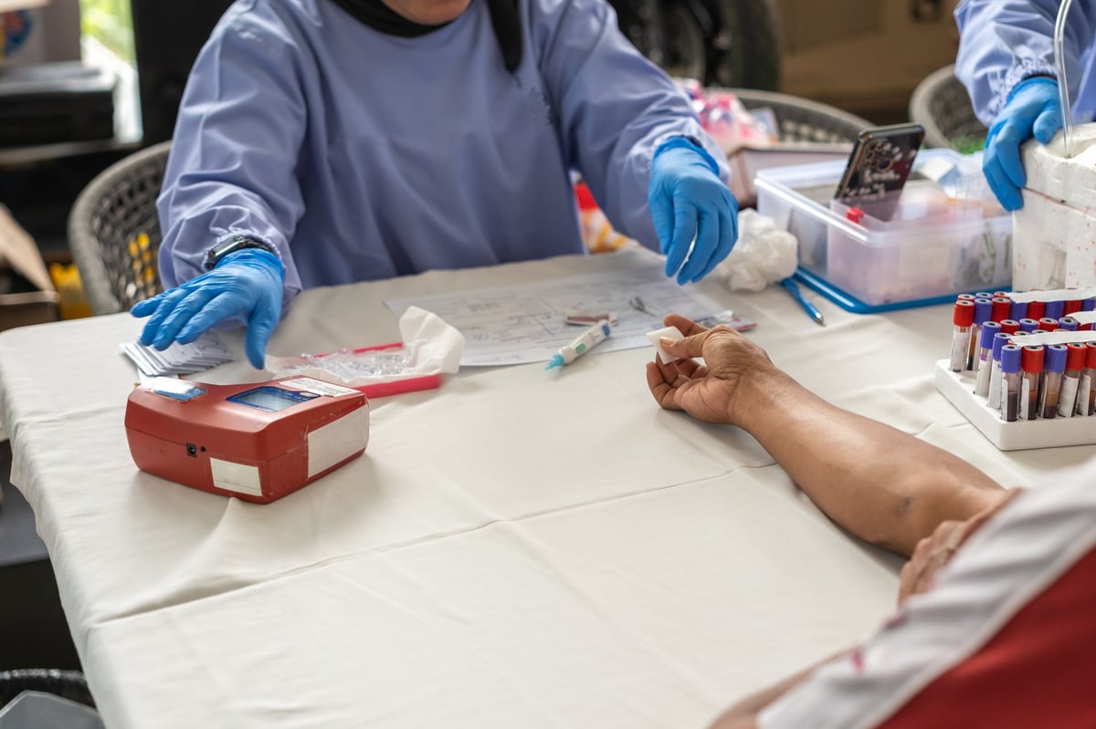 A healthcare worker in gloves collecting a blood sample into tubes for laboratory testing