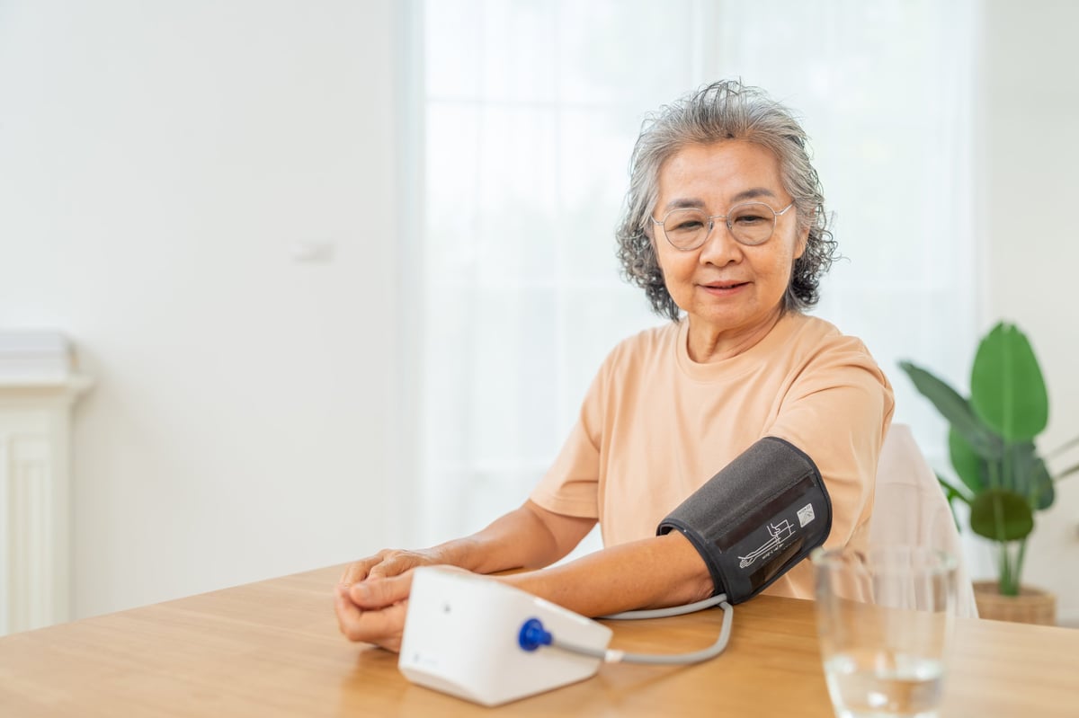 A senior woman using a digital blood pressure monitor for a wellness check at home