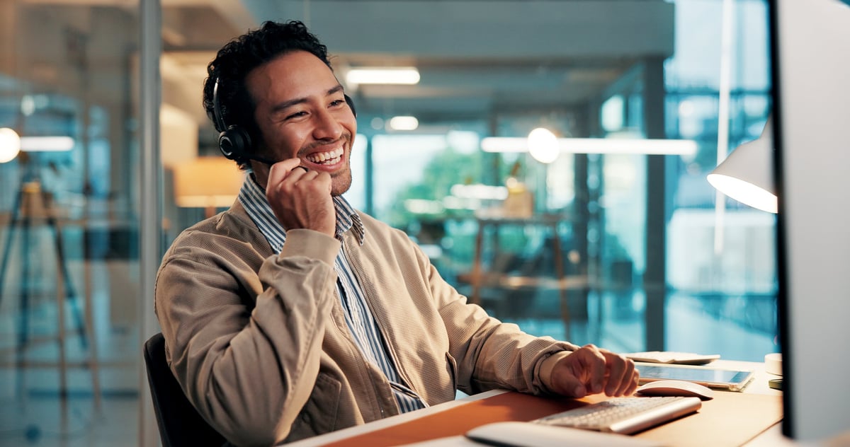 A friendly support team member in a headset helping a customer at a desk